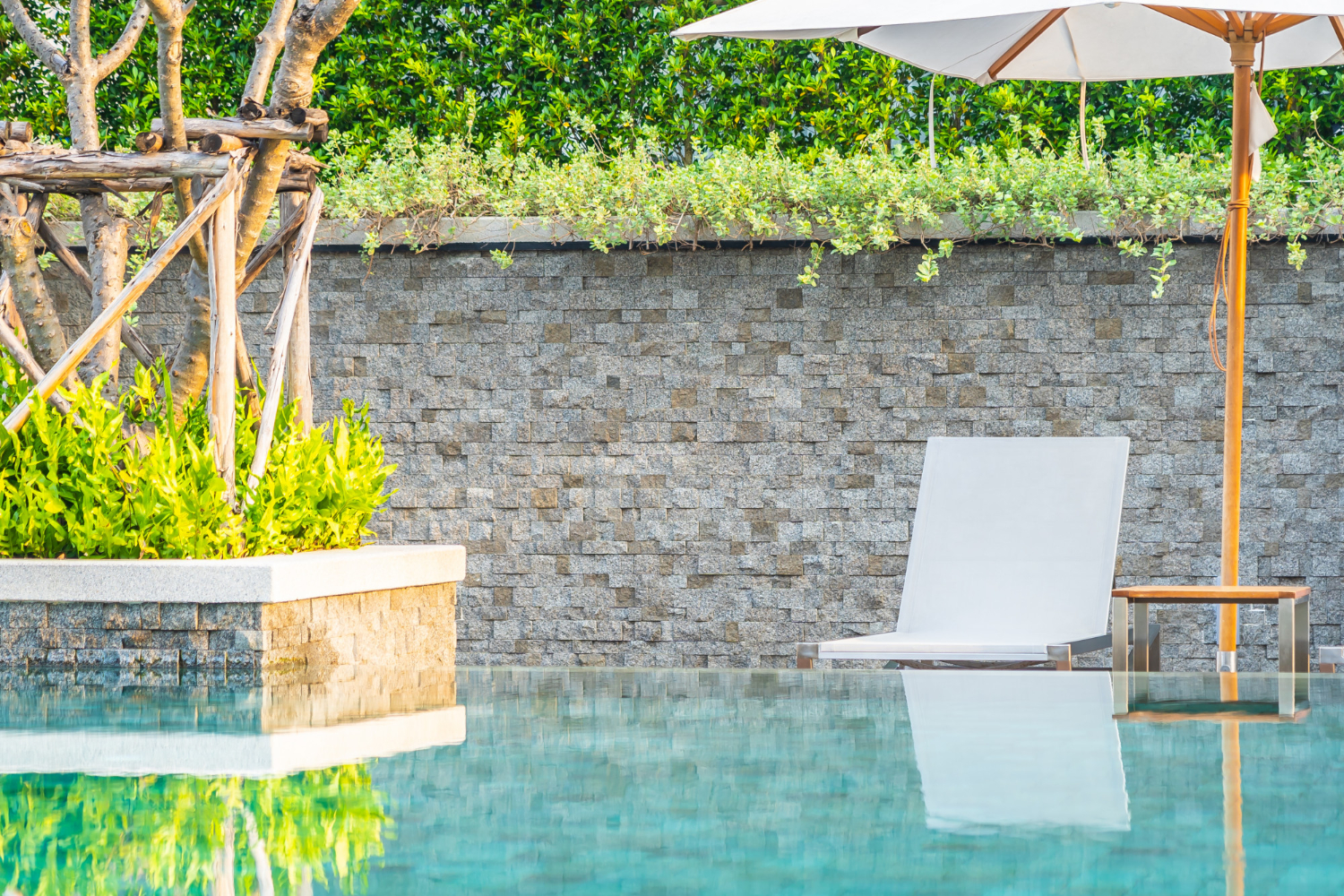 Piscine avec muret et terrasse en arrière plan